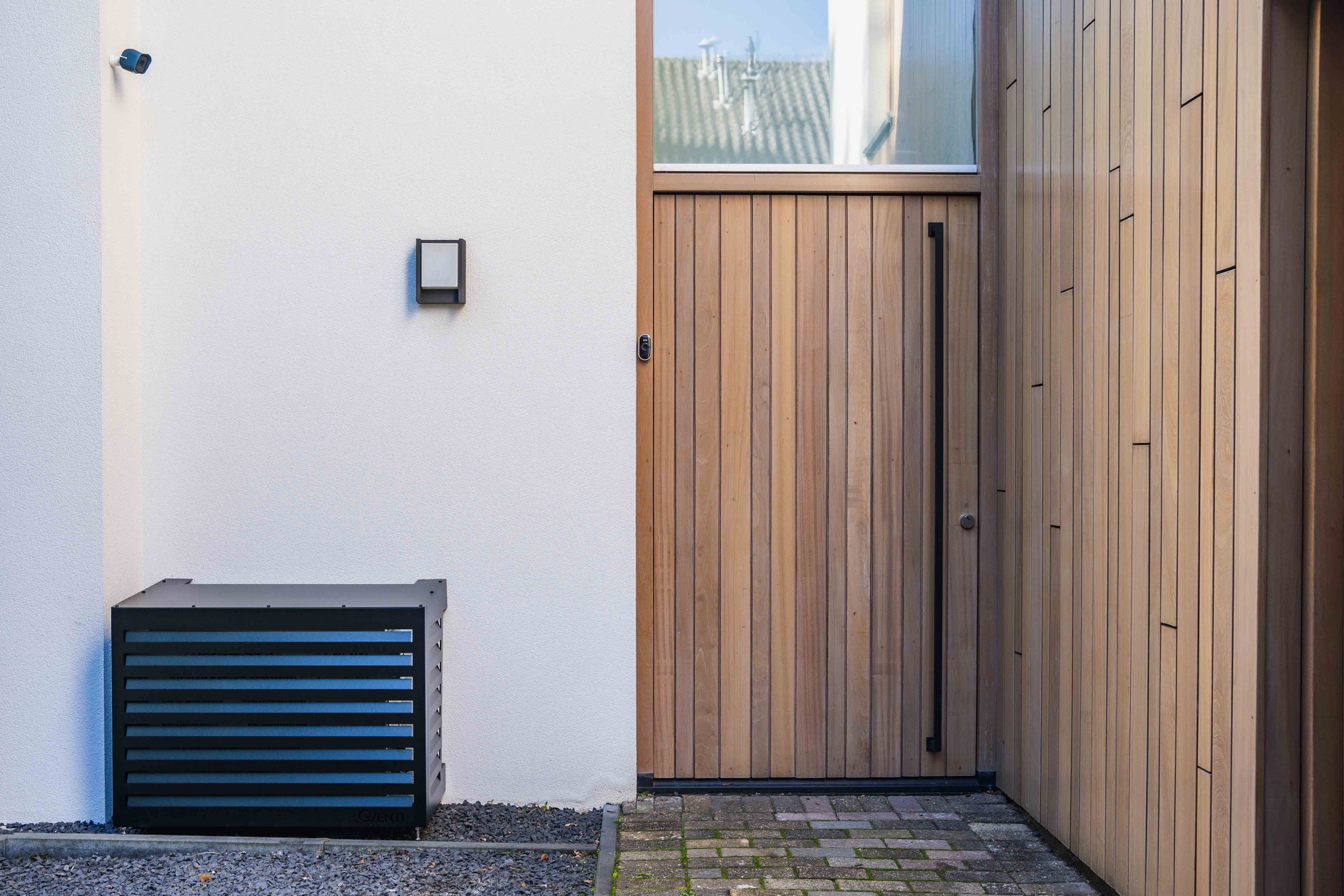 Qventi Airco cover voor buitenunit zwart naast buitendeur